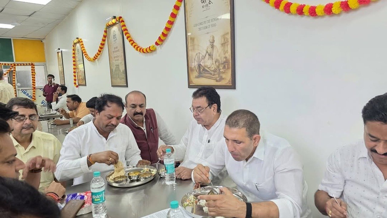 बापू की रसोई में साथ बैठकर भोजन करते कांग्रेस नेता — दीवार पर बापू की तस्वीर
