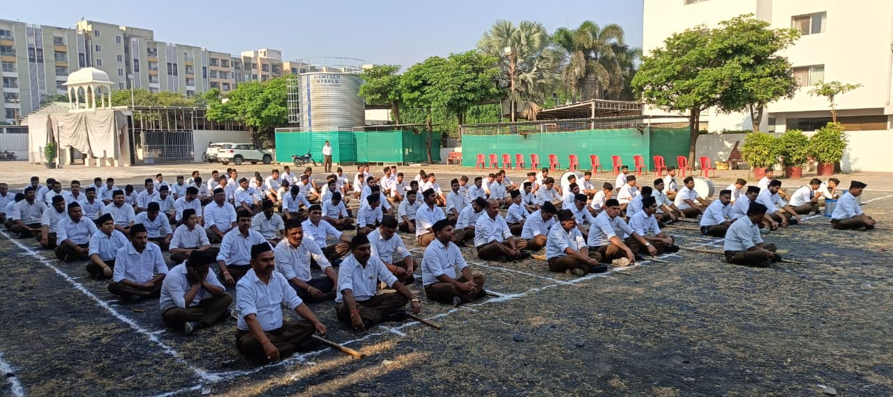 इंदौर में संघ शताब्दी वर्ष के पथ संचलन के एकत्रीकरण स्थल पर मैदान में सभा कर रहे स्वयंसेवक (वास्तविक तस्वीर)