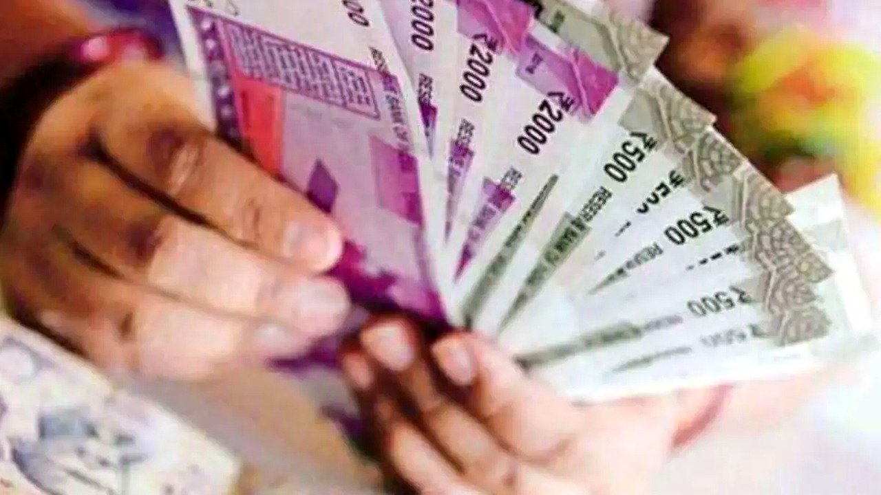 हाथों में भारतीय मुद्रा के नोट — न्यूनतम वेतन बढ़ोतरी